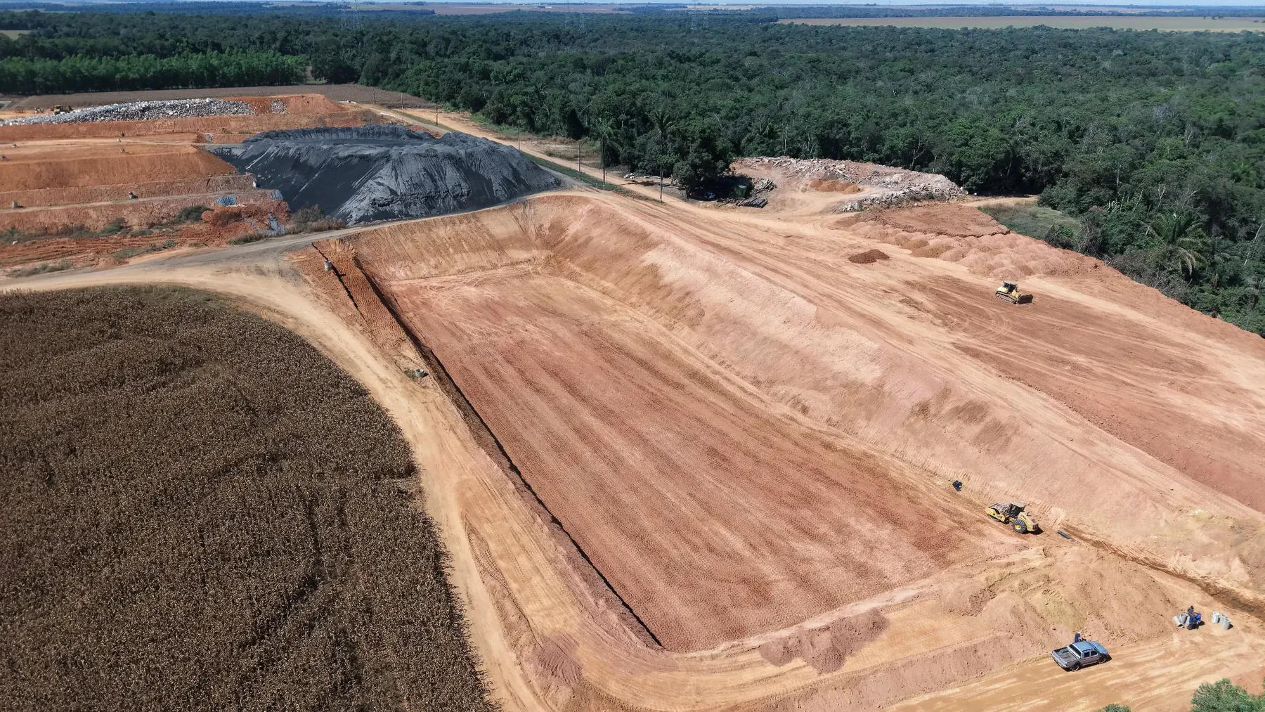 Vista aérea ampla da célula do aterro sanitário da Sanorte com máquinas e escala de execução